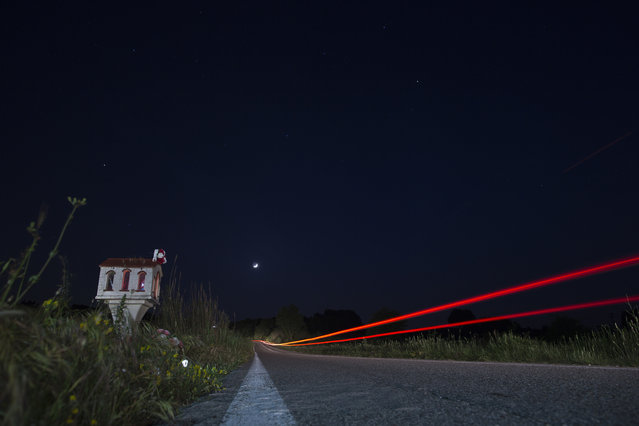 In this photo taken with a slow shutter speed on Friday, April 28, 2017, a car passes a roadside shrine near the village of Efyra, in the Peloponnese region of southern Greece. The shrine marks the spot where at dusk on October 18, 2009, 19-year-old Nikos Staikopoulos lost control of his speeding car, crashed and died. Tens of thousands of such shrines punctuate Greece’s roadside scenery, a common sight in a country that has one of the European Union’s worst road fatality rates. (Photo by Petros Giannakouris/AP Photo)