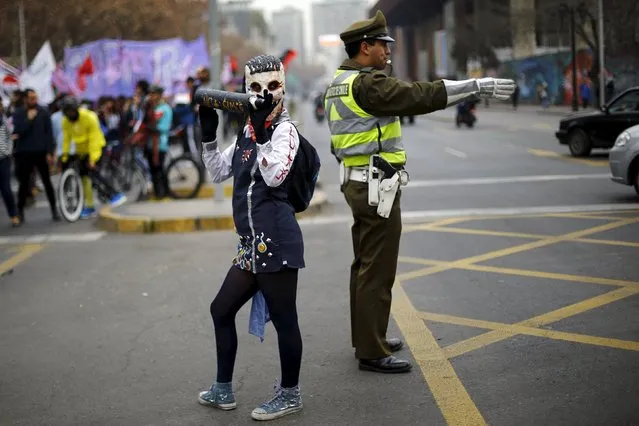 A demonstrator wearing a mock school uniform costume is pictured next to a traffic police officer during a rally held to support women's rights to an abortion in Santiago, Chile, July 25, 2015. (Photo by Ivan Alvarado/Reuters)