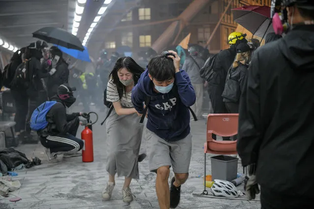 Protesters run for cover after riot police fired tear gas towards the bridge they were climbing down to the road below, to escape from Hong Kong Polytechnic University campus and from police, in Hung Hom district in Hong Kong on November 18, 2019. Dozens of Hong Kong protesters escaped a besieged university campus on November 18 by lowering themselves on a rope from a footbridge to a highway, AFP video showed. Once on the road they were seen being picked up by waiting motorcyclists. (Photo by Anthony Wallace/AFP Photo)