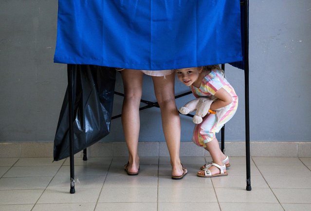 A girl looks from a voting booth at a polling station during the general election in Athens on June 25, 2023. Greek voters head to the polls again on June 25 in an election where conservative front-runner Kyriakos Mitsotakis is seeking a second term and an absolute parliamentary majority to form a “stable government”. (Photo by Aris Messinis/AFP Photo)