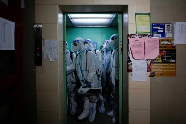Workers in protective suits take an elevator as they disinfect a residential area during lockdown, amid the coronavirus disease (COVID-19) pandemic, in Shanghai, China, May 18, 2022. (Photo by Aly Song/Reuters)