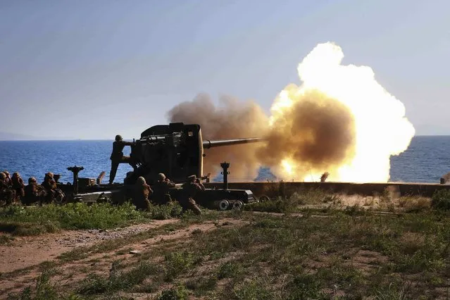 Soldiers fire an artillery piece during a visit by North Korean leader Kim Jong Un to inspect the defence detachment on Ung Islet, which is defending an outpost in the East Sea of Korea, in this undated photo released by North Korea's Korean Central News Agency (KCNA) in Pyongyang July 7, 2014. (Photo by Reuters/KCNA)