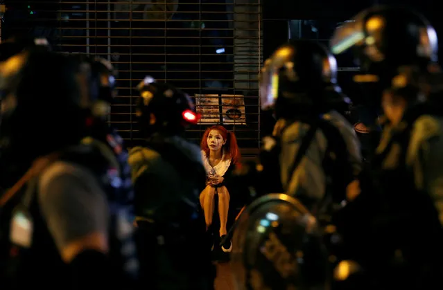 Riot policemen walk past a woman wearing Halloween make-up as they advance to protesters during Halloween in Hong Kong, China on October 31, 2019. (Photo by Kim Kyung-Hoon/Reuters)