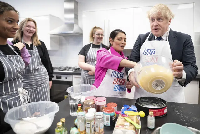 Home Secretary Priti Patel looks on as Prime Minister Boris Johnson tries his hand at baking during a visit to the HideOut Youth Zone, in Manchester on Sunday, October 3, 2021. (Photo by Stefan Rousseau/AP Photo)