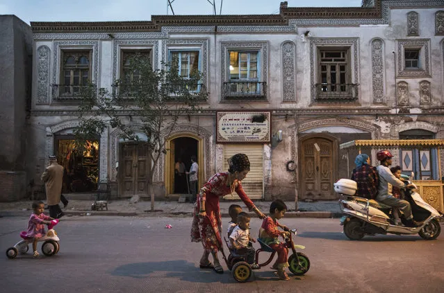 An ethnic Uyghur woman pushes her children on a tricycle on June 28, 2017 in the old town of Kashgar, in the far western Xinjiang province, China. (Photo by Kevin Frayer/Getty Images)