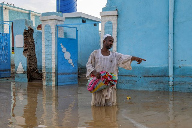 A holds salvaged items as he stands in a flooded area in al-Sagai north of Omdurman on August 6, 2023. Torrential rains have destroyed more than 450 homes in Sudan's north, state media reported on August 7, validating concerns voiced by aid groups that the wet season would compound the war-torn country's woes. Changing weather patterns saw Sudan's Northern State buffeted with heavy rain, causing damage to at least 464 houses, state-run SUNA news agency said. (Photo by AFP Photo/Stringer)