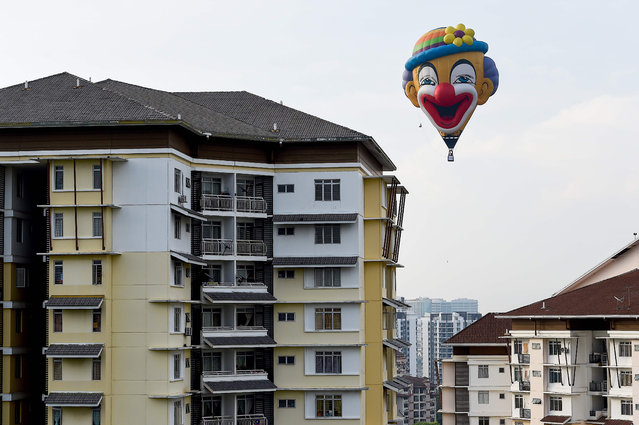 In this aerial photo taken on March 28, 2019 a hot air balloon flies over buildings in Putrajaya during the international hot air balloon festival in Putrajaya. (Photo by Mohd Rasfan/AFP Photo)