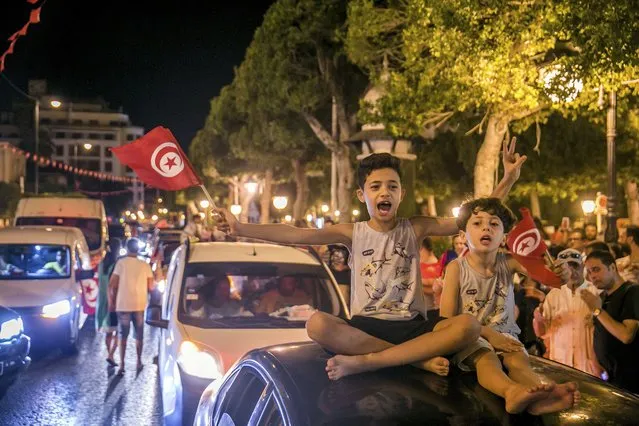 Tunisians celebrate the exit polls indicating a vote in favor of the new Constitution, in Tunis, late Monday, July 25, 2022. Hundreds of supporters of Tunisian President Kais Saied took to the streets to celebrate after the end of voting on a controversial new constitution that critics say could reverse hard-won democratic gains and entrench a presidential power grab. (Photo by Riadh Dridi/AP Photo)