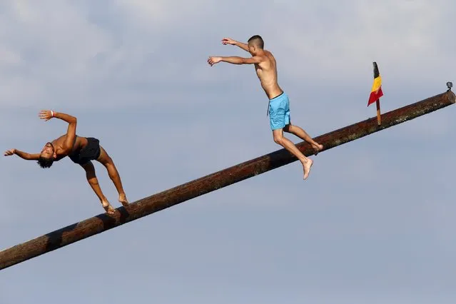 Two man jump off the “gostra”, a pole covered in grease, after running up during the children's competition to help remove some grease, during the celebrations for the religious feast of St Julian, patron of the town of St Julian's, outside Valletta, August 30, 2015. (Photo by Darrin Zammit Lupi/Reuters)