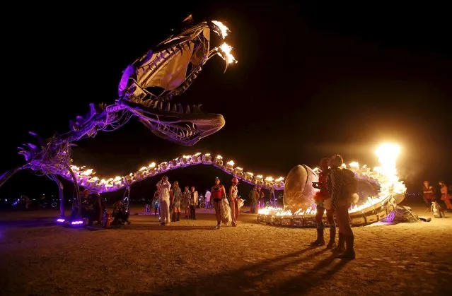 People gather at the art installation Serpent Mother during the Burning Man 2015 “Carnival of Mirrors” arts and music festival in the Black Rock Desert of Nevada, September 1, 2015. Participants are still arriving from all over the world for the sold-out festival to spend a week in the remote desert to experience art, music and the unique community that develops. (Photo by Jim Urquhart/Reuters)