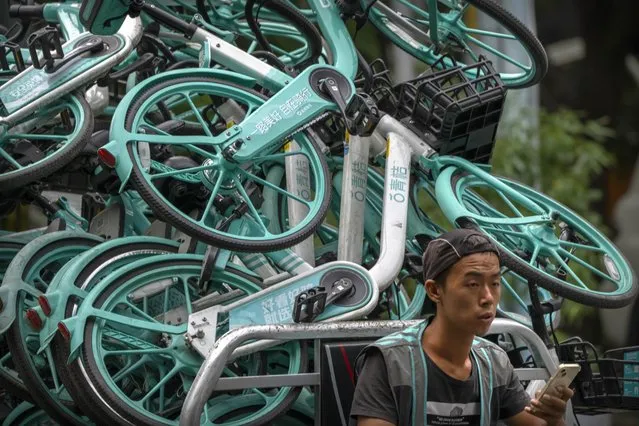 A worker drives a cart loaded with bicycles for a bike sharing app along a street in Beijing, Friday, August 26, 2022. (Photo by Mark Schiefelbein/AP Photo)