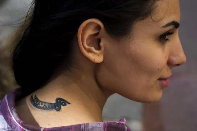 In this Wednesday, May 25, 2016 photo, Farah Najm, 21, an aviation maintenance student, poses for a photo showing her tattoo of the sword of Shiite Muslims' first Imam Ali, in Beirut, Lebanon. (Photo by Hassan Ammar/AP Photo)