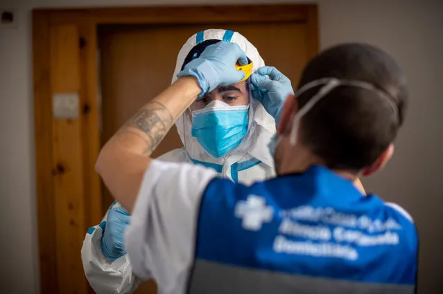Member of the technical support team Joan Alcaraz (R) helps healthcare worker ff the CAP Manso primary care centre, Kilian Trenard, to put his protective suit on before visiting patients at their homes in Barcelona on May 1, 2020. Spain registered 281 deaths from coronavirus in the past 24 hours, bringing the total toll to 24,824, confirming the slowdown in the pandemic, according to figures released. (Photo by Josep Lago/AFP Photo)