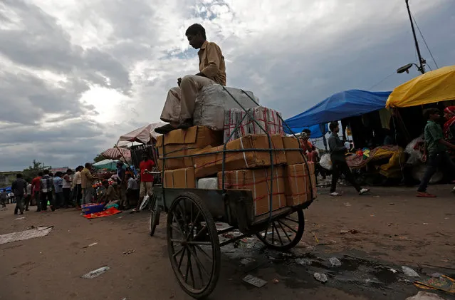 A labourer sits on top of a rickshaw loaded with boxes at a wholesale market in the old quarter of Delhi, India, August 2, 2016. (Photo by Adnan Abidi/Reuters)