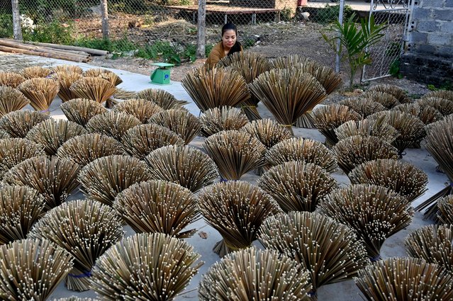A worker arranges dried incense sticks to dry in a courtyard in Quang Phu Cau village on the outskirts of Hanoi on January 21, 2025, ahead of Lunar New Year celebrations, known in Vietnam as Tet. Families living and working in the “incense village” of Quang Phu Cau now also make sticks in yellow, blue and green, catering to visitors eager to snap shots for Instagram. (Photo by Nhac Nguyen/AFP Photo)