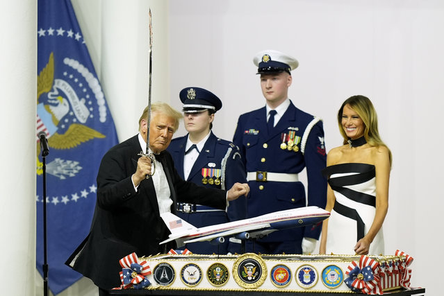President Donald Trump, left, holds a sabre after using it to cut a cake as first lady Melania Trump, right, watches at the Commander in Chief Ball, Monday, January 20, 2025, in Washington. (Photo by Alex Brandon/AP Photo)