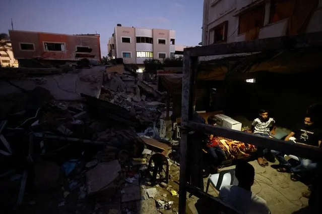 Palestinians sit in a shelter at the rubble of their house destroyed in the three-day Israel-Gaza fighting, in Gaza City on August 14, 2022. (Photo by Mohammed Salem/Reuters)