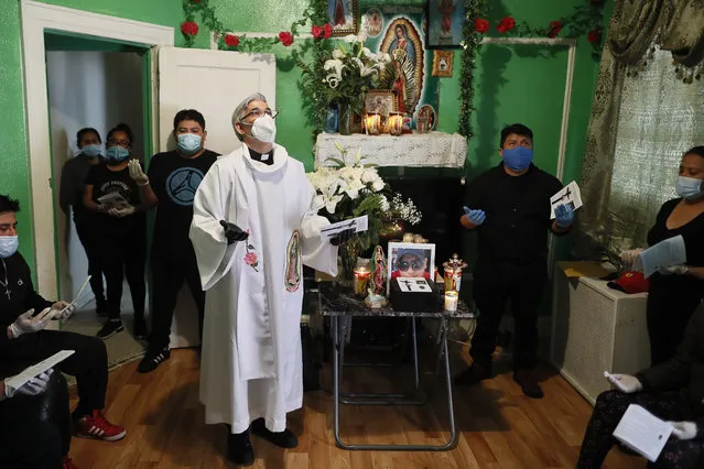 The Rev. Fabian Arias performs an in-home service beside the remains of Raul Luis Lopez who died from COVID-19 the previous month, Saturday, May 9, 2020, in the Corona neighborhood of the Queens borough of New York. (Photo by John Minchillo/AP Photo)