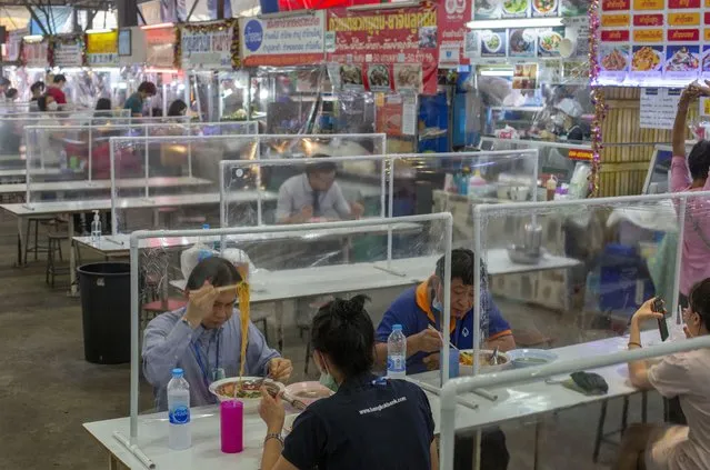 People eat in a food court divided by plastic sheets in Bangkok, Thailand, Tuesday, May 19, 2020. Thai government continue to ease restrictions related to running business in capital Bangkok that were imposed weeks ago to combat the spread of COVID-19. (Photo by Gemunu Amarasinghe/AP Photo)