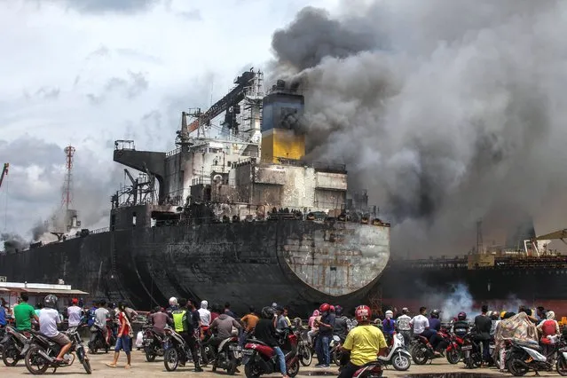 Resident local watches a crude oil tanker at the Waruna Shipyard that catches fire in Belawan port on May 11, 2020. The 21-year-old tanker, Jag Leela, a ship shrouded in thick smoke as several explosions occurred while being undergo treatment or docking at Waruna Shipyard in Belawan, on Monday morning. At least two deaths and 22 other workers suffered burns and were hospitalized. Some were reportedly still missing, trapped inside the ship that was being repaired. (Photo by Albert Ivan Damanik/ZUMA Wire/Rex Features/Shutterstock)