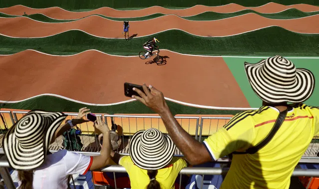 Colombian fans watch as Mariana Pajon of Colombia, background, competes in the women's seeding run at the Olympic BMX Center during the 2016 Summer Olympics in Rio de Janeiro, Brazil, Wednesday, August 17, 2016. (Photo by Pavel Golovkin/AP Photo)