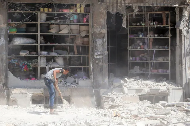 A civilian removes the rubble in front of a damaged shop after an airstrike in the rebel held al-Saleheen neighborhood of Aleppo, Syria August 18, 2016. (Photo by Abdalrhman Ismail/Reuters)