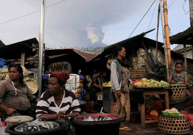 Balinese sell produce at a streetside market as Mount Agung volcano erupts at Culik village market in Karangasem, Bali, Indonesia on November 27, 2017. (Photo by Johannes P. Christo/Reuters)