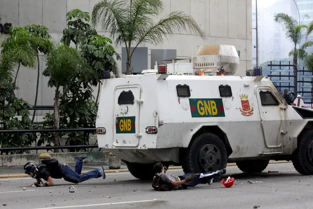 Demonstrators fall on the ground after being hit by a riot police armoured vehicle while clashing with the riot police during a rally against Venezuelan President Nicolas Maduro in Caracas, Venezuela, May 3, 2017. Marco Bello: “In that moment, demonstrators attacked a couple of National Guards when they fell off a bike during clashes. Then another National Guard driving an armoured vehicle ran over the motorbike, trying to intimidate demonstrators and to rescue their fellow guards. The reaction of the crowd was to attack, throwing rocks and molotov cocktails and trying to jump over the truck. In the midst of confrontation and confusion, the driver drove back hitting people”. (Photo by Marco Bello/Reuters)