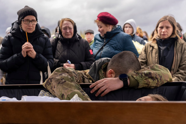 A brother in arms of Marharyta Polovinko, 31, Ukrainian artist, paramedic and volunteer from 3rd Assault brigade, who was killed recently on the frontline, mourns over her coffin during the funeral ceremony in Krivyi Rih, Ukraine, Friday, April 11, 2025. (Photo by Alex Babenko/AP Photo)
