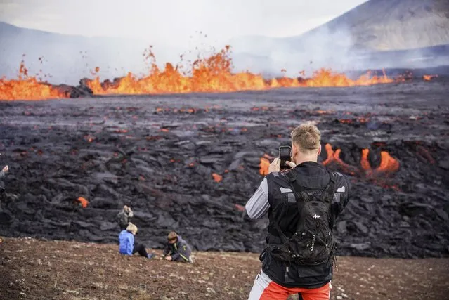 People look at the lava flowing on Fagradalsfjall volcano in Iceland on Wednesday August 3, 2022, which is located 32 kilometers (20 miles) southwest of the capital of Reykjavik and close to the international Keflavik Airport. (Photo by Marco Di Marco/AP Photo)