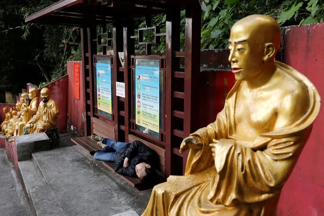 A man takes a nap between life-size gilded Arhan statues at Ten Thousand Buddhas Monastery in Hong Kong, China December 12, 2017. (Photo by Tyrone Siu/Reuters)