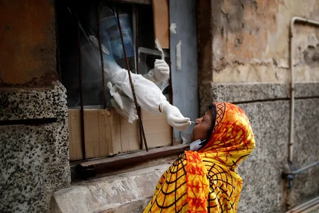 A health worker in personal protective equipment (PPE) collects a sample using a swab from a person at a local health centre to conduct tests for the coronavirus disease (COVID-19), amid the spread of the disease, in the old quarters of Delhi, India, August 14, 2020. (Photo by Adnan Abidi/Reuters)