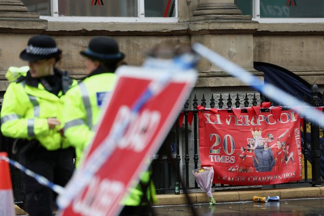 Police officers operate as a Liverpool FC flag is seen in the background at the site of an incident where a car plowed into a crowd of Liverpool fans during a parade celebrating their side's Premier League soccer title, in central Liverpool, Britain, on May 27, 2025. (Photo by Isabel Infantes/Reuters)