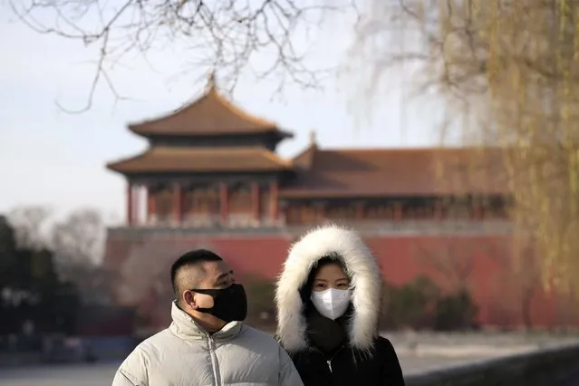 Residents wearing masks walk near the forbidden city in Beijing, Wednesday, December 14, 2022. China's National Health Commission scaled down its daily COVID-19 report starting Wednesday in response to a sharp decline in PCR testing since the government eased antivirus measures after daily cases hit record highs. (Photo by Ng Han Guan/AP Photo)