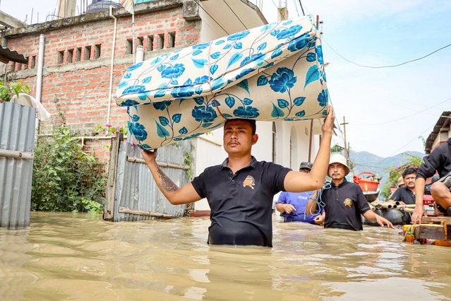 A man carries a mattress as he wades through floodwaters at Kongba in Imphal East on June 3, 2025. Flash floods and landslides after torrential monsoon rain over the last two days killed at least 30 people in India's northeast, officials said on June 1. (Photo by AFP Photo/Stringer)