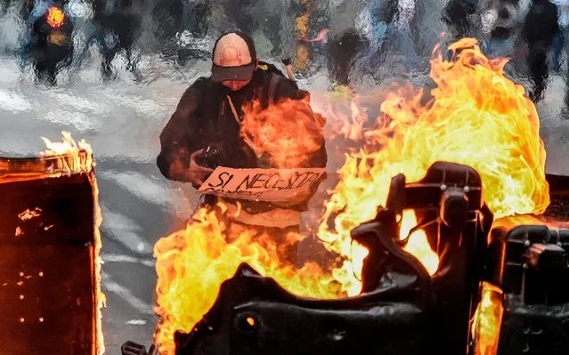 A man stands behind a burning barricade during the fifth straight day of protests against police brutality in Bogota on September 13, 2020. Bogota's Mayor Claudia Lopez, apologized this Sunday for the abuses of the public force, in a ceremony that gathered relatives of the dead and wounded during the bloody protests that broke out five days ago against police brutality in Colombia. (Photo by Juan Barreto/AFP Photo)