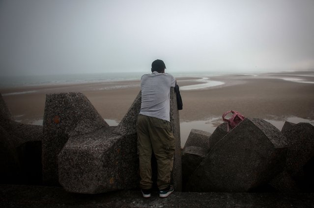 A migrant waits on a pier before the arrival of an inflatable dinghy in an attempt to cross the English Channel to reach Britain, at the beach of Petit-Fort-Philippe in Gravelines, near Calais, France on July 2, 2025. (Photo by Gonzalo Fuentes/Reuters)