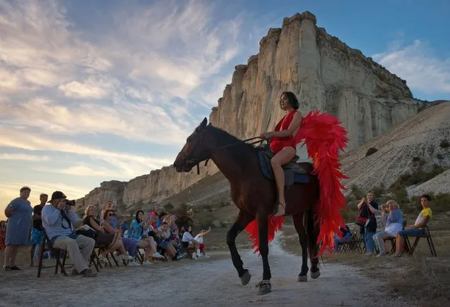 A model wearing a creation rides a horse during an outdoor fashion show for collections by Crimean designers near Ak-Kaya Rock in Belgorsk District of Crimea, Russia, during the 2020 Crimean Fashion Week on September 13, 2020. (Photo by Sergei Malgavko/TASS)
