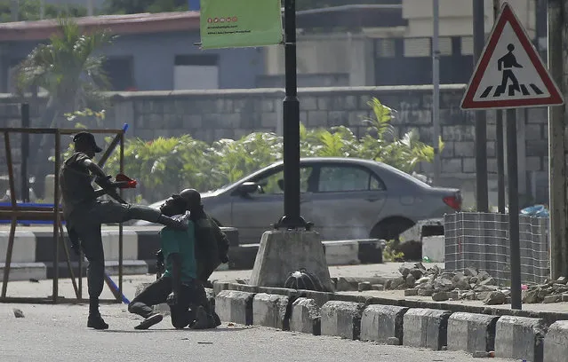 Police officers detain a protester at the Lekki toll gate in Lagos, Nigeria, Wednesday October 21, 2020. After 13 days of protests against alleged police brutality, authorities have imposed a 24-hour curfew in Lagos, Nigeria's largest city, as moves are made to stop growing violence. (Photo by Sunday Alamba/AP Photo)