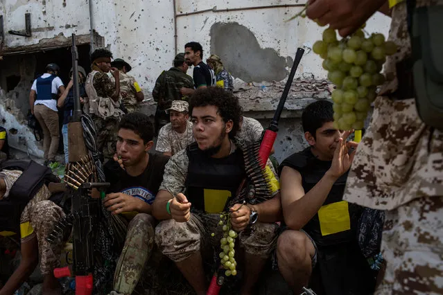 Fighters loyal to Libya's Government of National Accord eat grapes during a break on the western frontline against Islamic State (IS) group members in Sirte on October 2, 2016. A Dutch journalist was killed by sniper fire while covering clashes in Libya's coastal city of Sirte, as unity government forces battled Islamic State group holdouts in the jihadist bastion. (Photo by Fabio Bucciarelli/AFP Photo)
