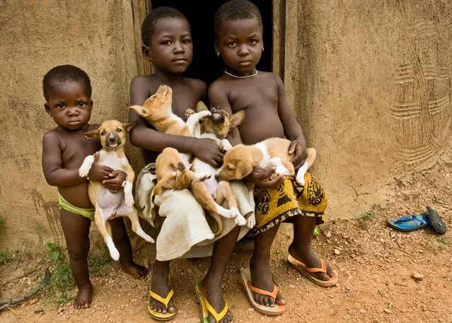 “We were traveling through Benin when an adobe building caught our eye. We stopped to photograph it and suddenly some children trailed by puppies appeared. This image captures one of many serendipitous moments we encountered in our travels”. (Photo by Art Wolfe/Art Wolfe Stock)