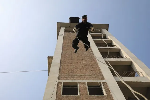 A police officer rappels off a building during a practice session at the Elite Police Training Centre in Nowshera, Pakistan on February 10, 2023. Newly graduated police officers are trained at the vast Elite Police Training Center for six months, where they are taught how to conduct raids, to rappel from buildings with a rope and use rocket-propelled grenades and anti-aircraft guns, which they practice on a simulated militant training camp. (Photo by Fayaz Aziz/Reuters)