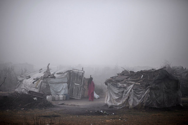A Pakistani woman stands outside her makeshift home in a slum during a foggy and cold morning in Islamabad, Pakistan, Friday, January 4, 2013. (Photo by Muhammed Muheisen/AP Photo)