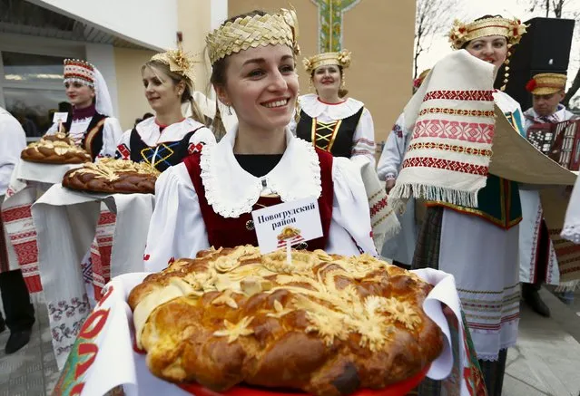 Women dressed in national clothes and holding loaves wait for the participants of the regional harvest festival in the town of Dyatlovo, Belarus, November 13, 2015. (Photo by Vasily Fedosenko/Reuters)