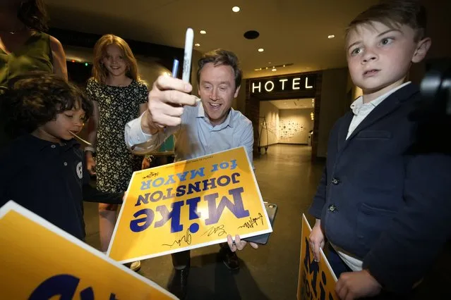 Denver mayoral candidate Mike Johnston autographs yard signs for the children of his supporters before entering an election eve watch party in a hotel late Tuesday, April 4, 2023, in lower downtown Denver. Johnston and Kelly Brough were the top vote-getters in the race, which featured 16 candidates. (Photo by David Zalubowski/AP Photo)