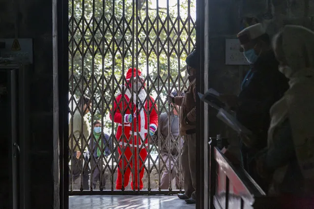 A visitor wearing a Santa Claus costume is stopped at the entrance as registered members of St. John in the Wilderness church, attend the Christmas mass in Dharmsala, India, Friday, December 25, 2020. The church which was built in 1852, is currently closed to general visitors due to COVID-19 restrictions. (Photo by Ashwini Bhatia/AP Photo)