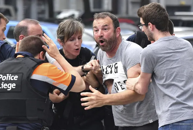 Police try to calm a man who crossed over a police line at the scene of a shooting in Liege, Belgium, Tuesday, May 29, 2018. A gunman killed three people, including two police officers, in the Belgian city of Liege on Tuesday, a city official said. Police later killed the attacker, and other officers were wounded in the shooting. (Photo by Geert Vanden Wijngaert/AP Photo)