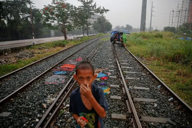 A boy stands on a railroad track as a man pushes passengers on a makeshift trolley in an area where, according to local residents, several people have been killed in police operations since the beginning of country's war on drugs, in Manila, Philippines November 2, 2016. (Photo by Damir Sagolj/Reuters)