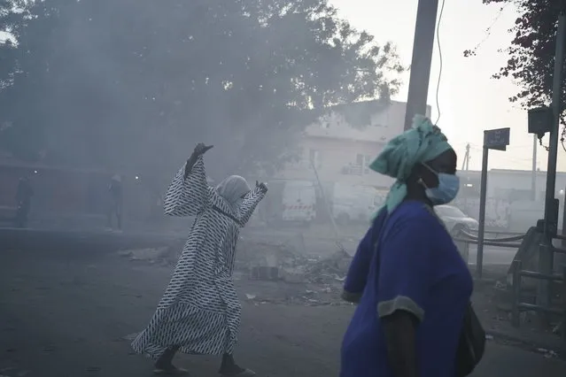 Women cross a street filled with smoke during clashes between demonstrators and police in Dakar, Senegal, Saturday, June 3, 2023. (Photo by Leo Correa/AP Photo)