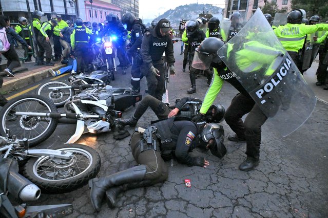 Police officers help injured colleagues after clashes erupted during a protest called by unions and social organizations against Daniel Noboa's government in downtown Quito on November 21, 2024. Drug-related violence, political turmoil, a faltering economy and blackouts lasting up to 14 hours a day mark the run-up to Ecuador's February presidential elections, in which President Daniel Noboa is seeking re-election. (Photo by Rodrigo Buendia/AFP Photo)